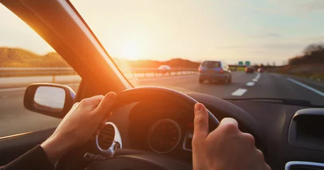 Foto op Plexiglas hands of car driver on steering wheel, road trip, driving on highway road © Song_about_summer