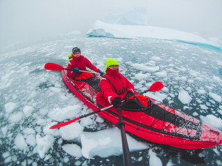 kayaking in Antarctica, couple of kayakers doing travel selfie with icebergs, extreme sport adventure honeymoon