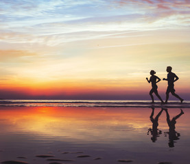 sport and health, two runners on the beach, silhouette of people jogging at sunset, man and woman...