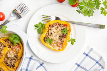 Stuffed yellow bell peppers, beef stew stuffing with vegetables and cheese. Light wooden background