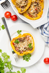 Stuffed yellow bell peppers, beef stew stuffing with vegetables and cheese. Light wooden background