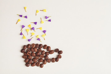 Cup of morning coffee made of coffee beans and colorful flowers on bright yellow background
