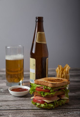 sandwich with beer, sauce, fried potatoes on a wooden table. Hor
