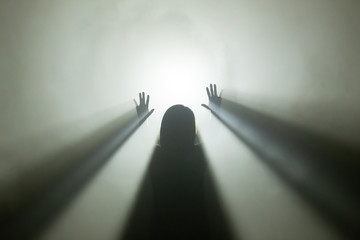 Licht am Ende des Tunnels - Silhoutte einer weiblichen Person im Gegellicht mit Nebel, die die...