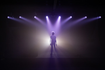 Fototapeta na wymiar Silhouette eines Mädchens mit Mikrofon auf einer Bühne im Rampenlicht mit Nebel