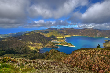 Bergsee tiefblau in der Sonne umgeben von Bergen und einem blauen Himmel und einen schönen Himmel