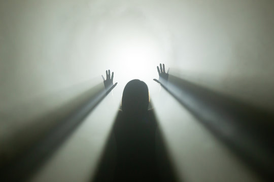 Licht am Ende des Tunnels - Silhoutte einer weiblichen Person im Gegellicht mit Nebel, die die H&auml;nde hebt