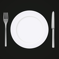 Food icon. White ceramic plate with metal fork and knife isolated on a dark background. Top view.