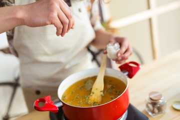 Young woman spicing up the food while cooking in an organic store.
