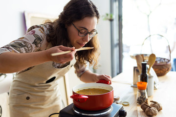 Beautiful woman tasting the food while cooking in an organic store.