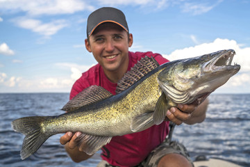 Happy fisherman with big zander fish trophy at the boat