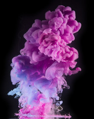 Colorful rainbow paint drops from above mixing in water. Ink swirling underwater.