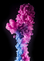 Colorful rainbow paint drops from above mixing in water. Ink swirling underwater.