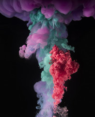 Colorful rainbow paint drops from above mixing in water. Ink swirling underwater.