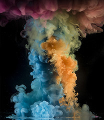 Colorful rainbow paint drops from above mixing in water. Ink swirling underwater.