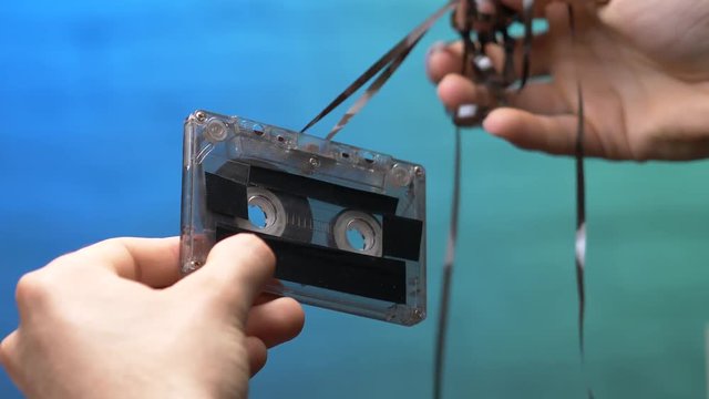 Destroying a music cassette tape by pulling the band.