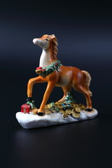 Little porcelain horse of a brown coloring, subject shooting against a dark background.
