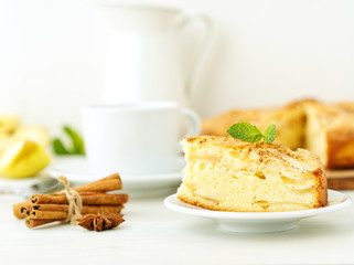 Breakfast with tea and homemade charlotte, apple pie and apple on wooden white background, side view, selective focus,