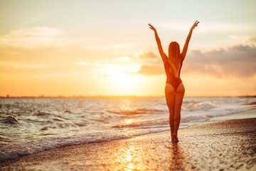 Fototapeta na wymiar carefree woman dancing in the sunset on the beach.