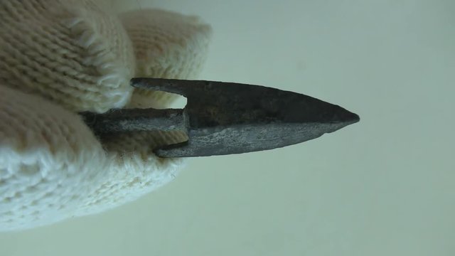 Archeologist inspects authentic ancient arrow head made of metal