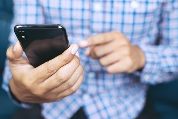 Young business man plaid shirt using on cell phone during rest in office. sitting sofa in watching message on mobile phone during break.	