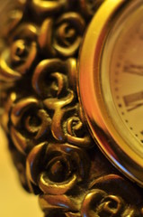 détail d'horloge de table avec décor de roses et cadran à chiffres romains en lumière jaune
