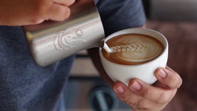 Close up man hands pouring coffee latte art.