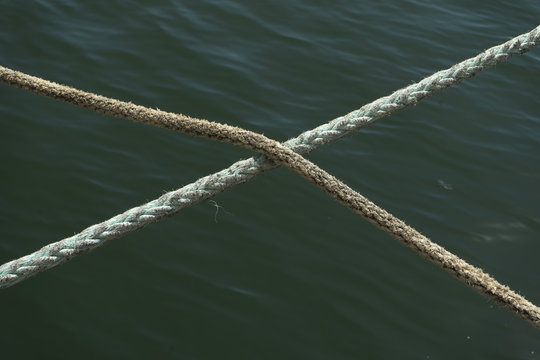two hennep fiber ropes crossing eachother in the middle with a ocean water background