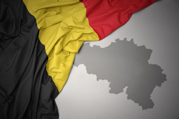 waving colorful national flag and map of belgium.