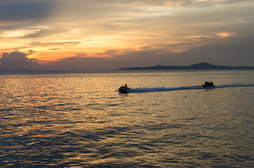 Naklejka na ściany i meble speed boat and banana boat into the sea with sunset