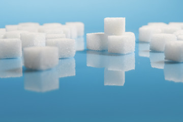 selective focus Group of Sugar cubes vary position on light blue background