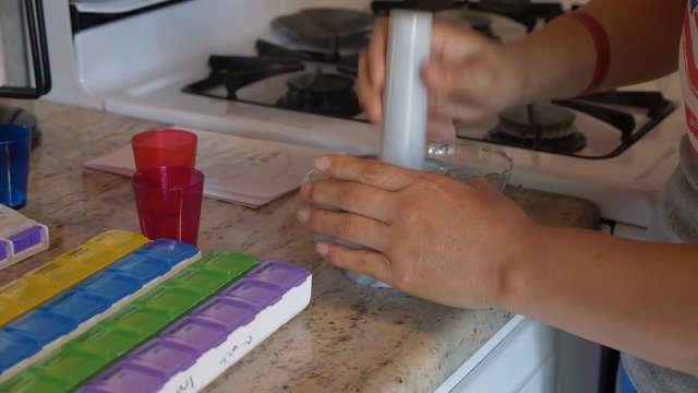A caregiver grinding prescription medications for elderly patients with a motar and pestle