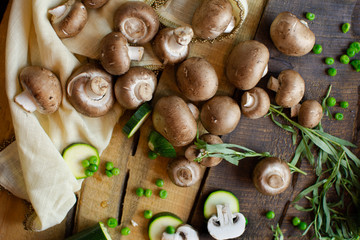 Rich organic vegetarian food flat lay with mushrooms sliced zucchini and peas on rustic wood background