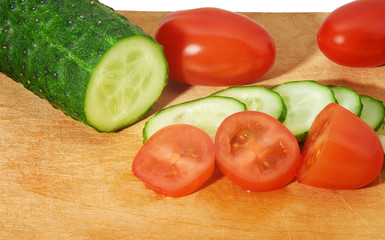 Cucumber and tomatoes on cutting board
