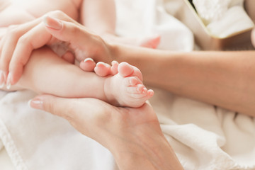 Obraz na płótnie Canvas Hands of woman holds baby foot