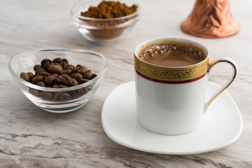 Vintage cup of turkish coffee and traditional bronze coffee pot served on marble