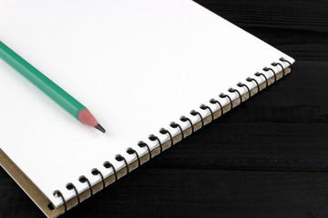 pencil on a notebook on a wooden dark background