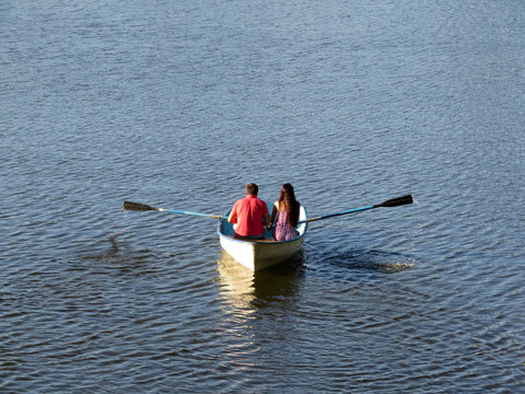 Couple in love sailing on a rowing boat in summer. Young man and woman in a boat, romantic date