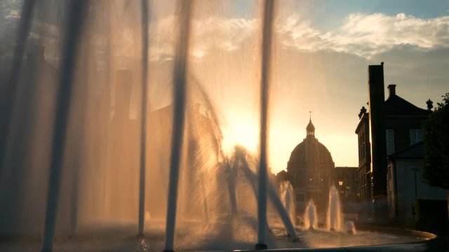 Timelapse view of Copenhagen skyline from behind a water fountain at sunset, Denmark.