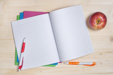 School notebook, pens and apple