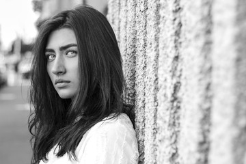 Portrait of a beautiful young woman with a mysterious look. Fashionable girl looks into the camera outdoors. 