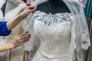 Seller's hands correcting bridal veil on mannequin in salon