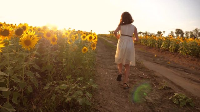 little girl running across the field with sunflowers at sunset. slow motion video. girl runner in the field at sunset sunflowers. girl sunlight runs the concept lifestyle of sunflowers