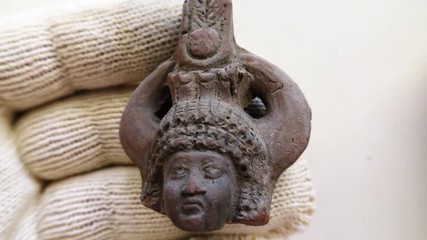 Archeologist inspects tiny ancient authentic clay head - Powered by Adobe