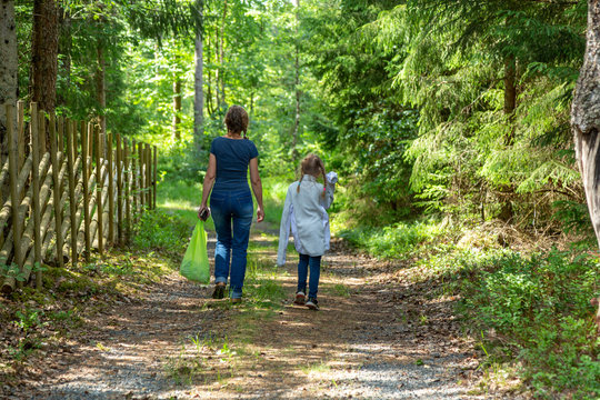 Mor och dotter promenerar på en väg genom skogen
