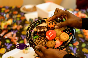 Halloween bake sale party Woman taking Halloween cookies off tray at Halloween office party