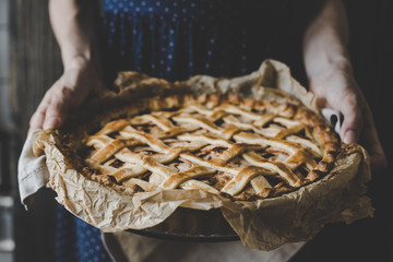 Hands holding homemade delicious apple pie. Close up