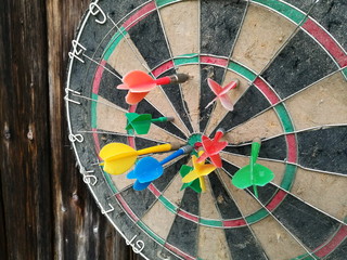 Alte Dartscheibe mit bunten Dartpfeilen auf der alten braunen Holztür einer Scheune im Sommer auf...