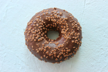 Doughnut in chocolate icing blue textured background close-up, top view