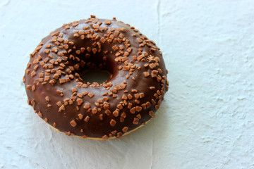 Doughnut in chocolate icing blue textured background close-up, top view